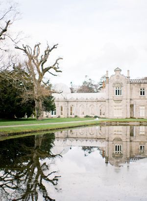 a large building sitting on top of a lush green field next to a body of water