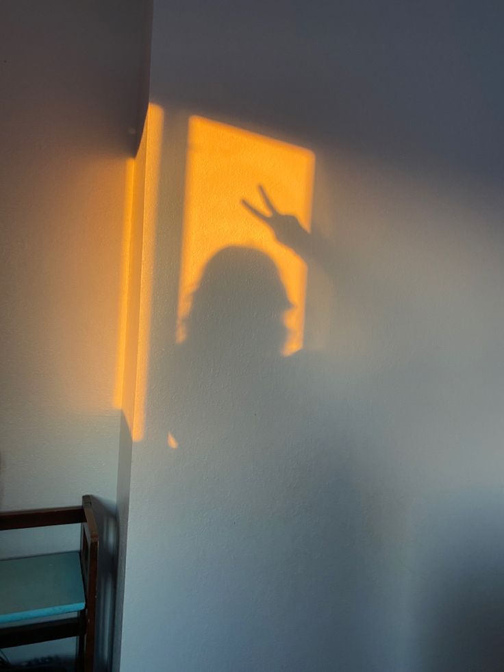 the shadow of a person's head on a wall next to a table and chair