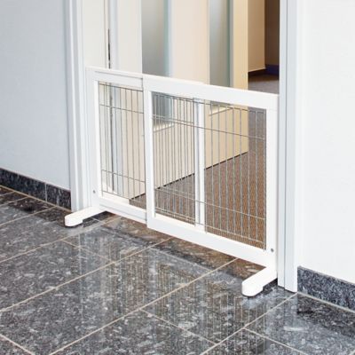 a white dog gate on the ground in front of a door with glass doors and windows