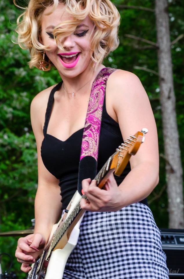 a woman with blonde hair playing an electric guitar