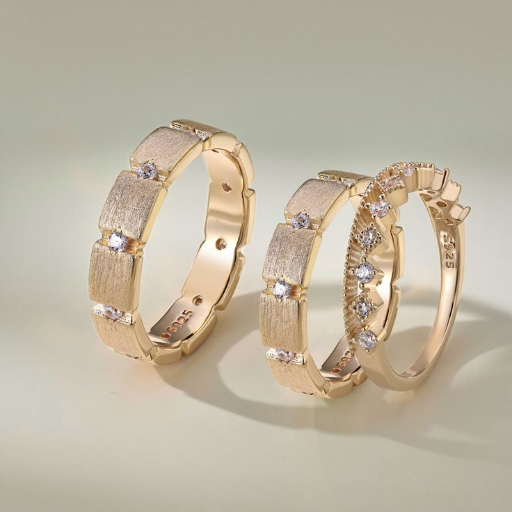 two gold wedding rings with diamonds on each one and an invisible band around the other