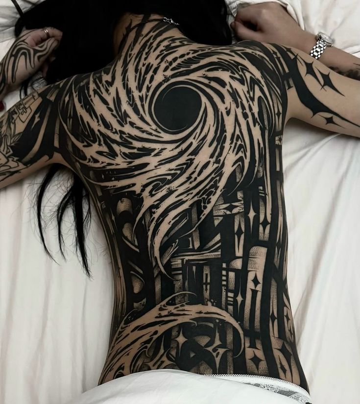 a woman laying on top of a bed covered in lots of black and white tattoos