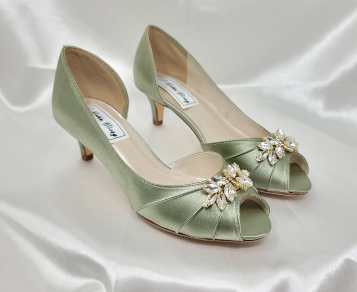 a pair of green high heeled shoes sitting on top of a white sheet