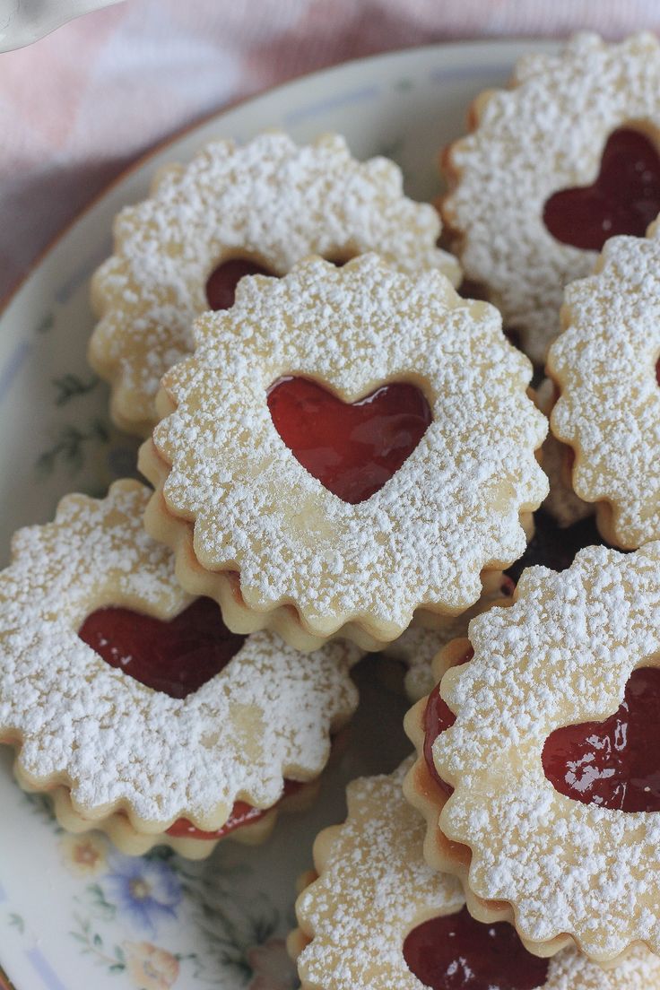 small heart shaped cookies with jelly filling on a plate