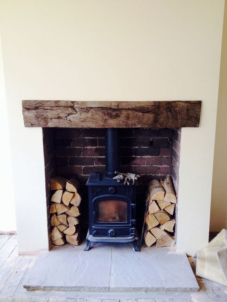 a fire place with logs stacked on the floor and a wood burning in it's fireplace