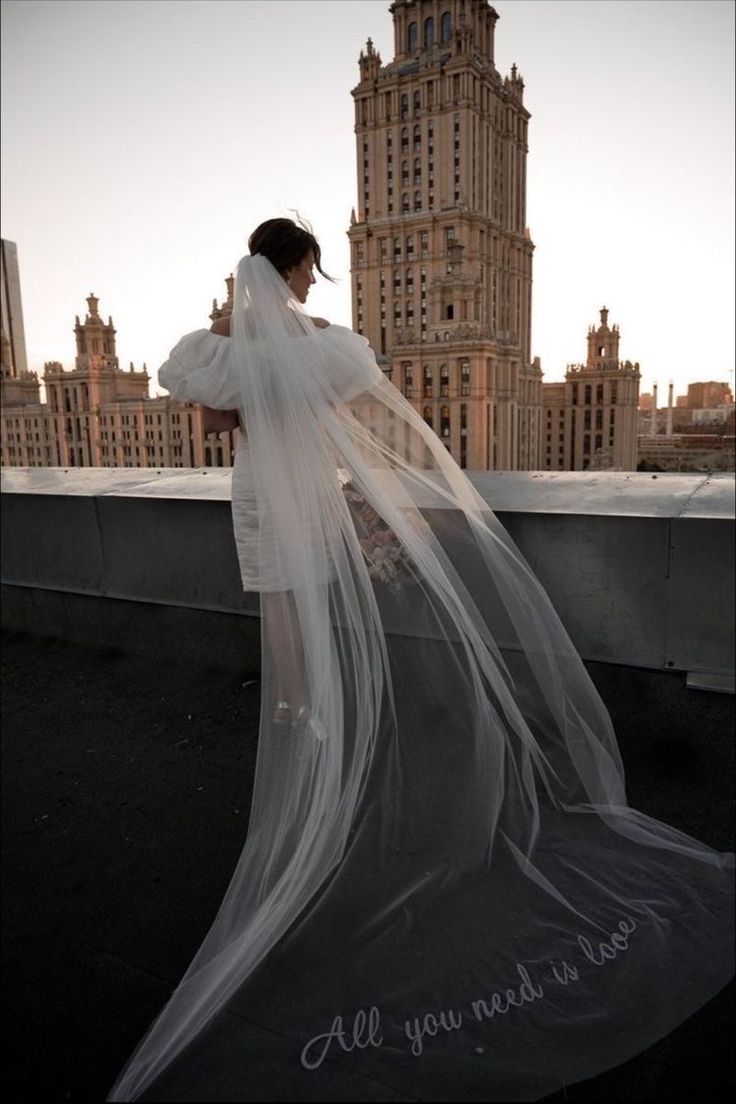 a woman wearing a veil on top of a roof with the words all you need is love written on it