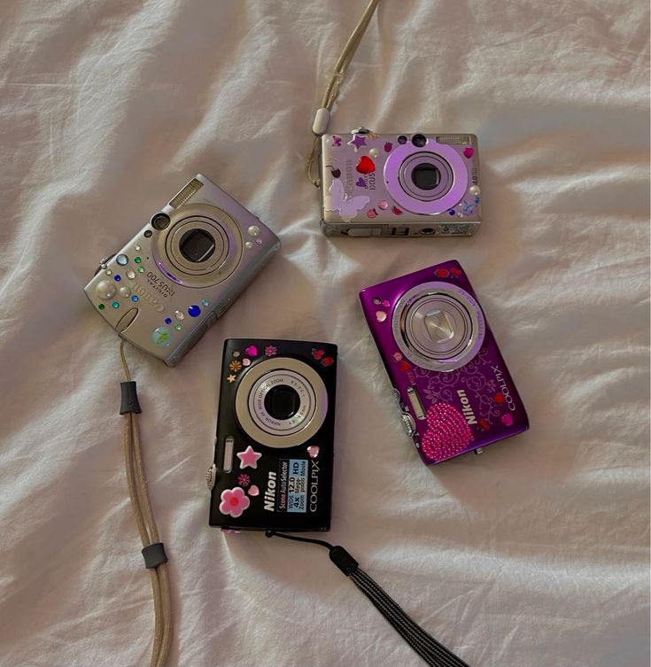 three different types of cameras laying on a bed