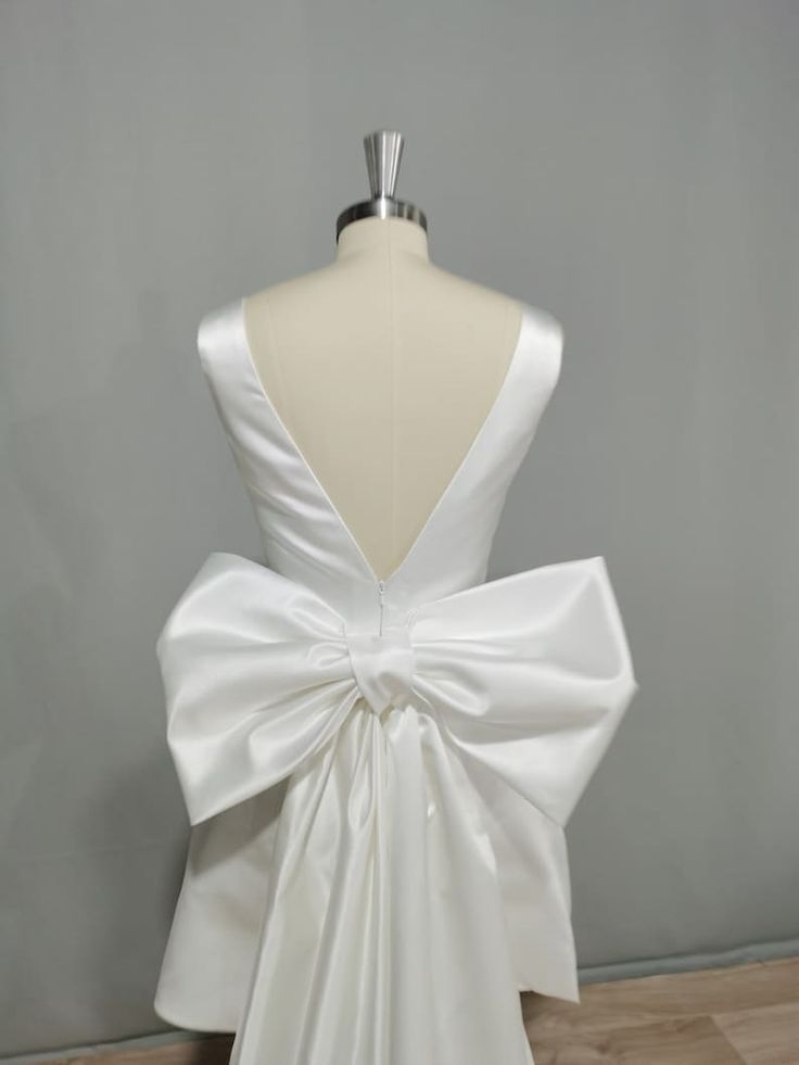 the back of a white wedding dress with a large bow