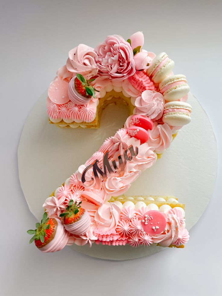 a white plate topped with a cake covered in pink frosting and strawberries on top of it