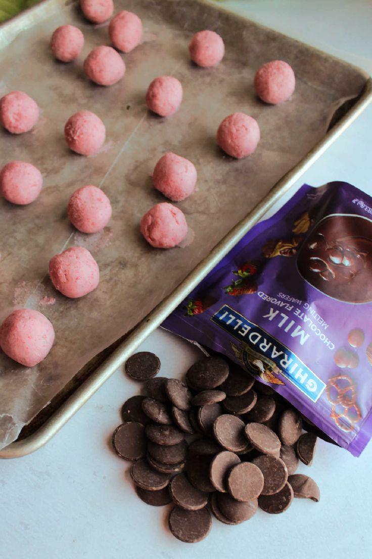 chocolate and pink doughnuts on a baking sheet next to a bag of milk