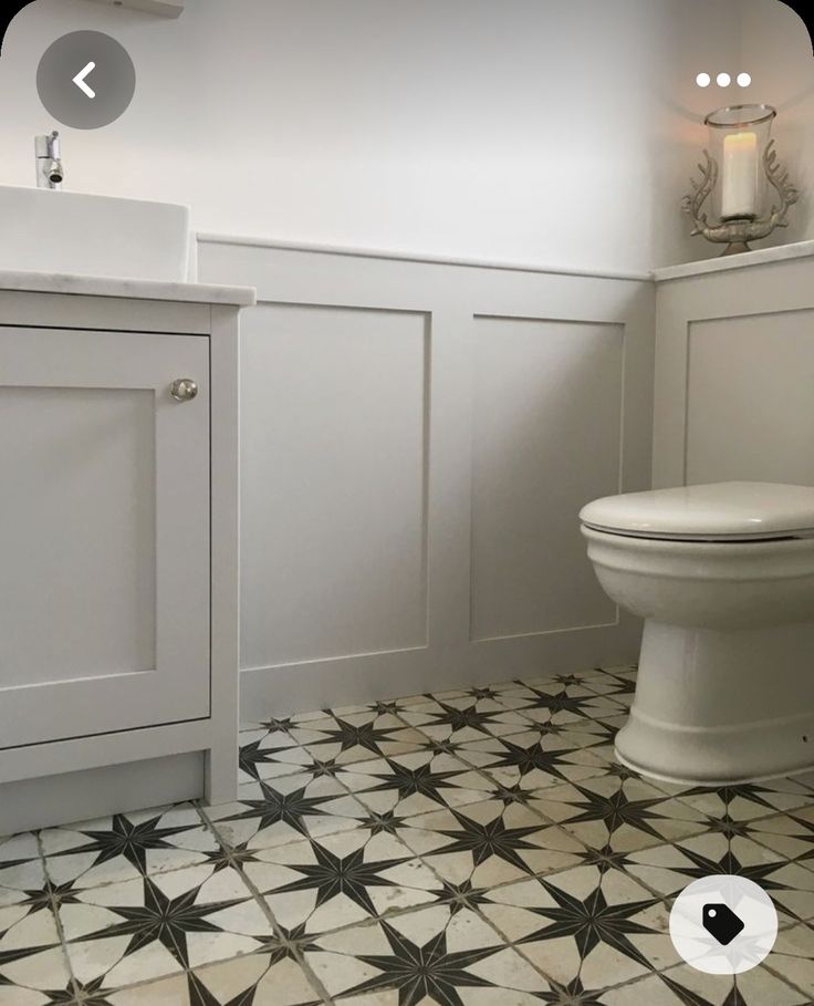 a white toilet sitting next to a sink in a bathroom under a window on top of a tiled floor