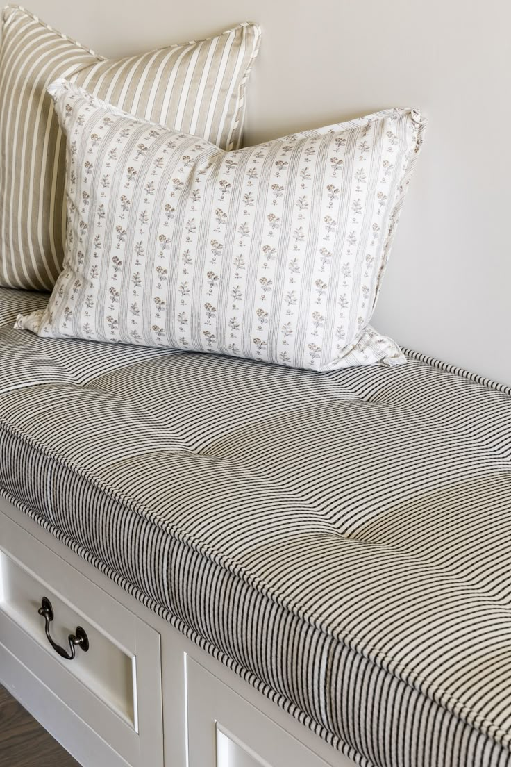 a bed with two pillows on top of it next to a white dresser and drawers