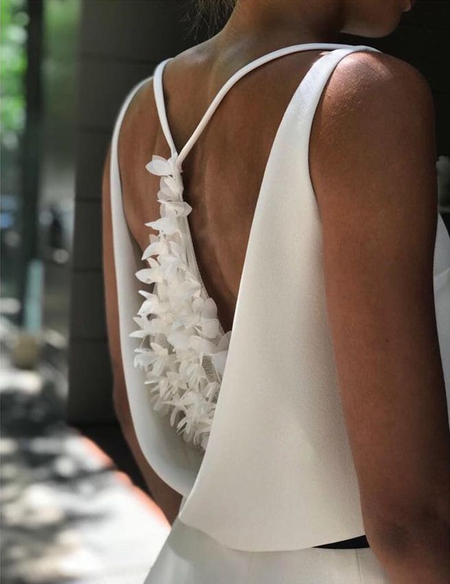 the back of a woman's dress with white flowers on it and an open neckline