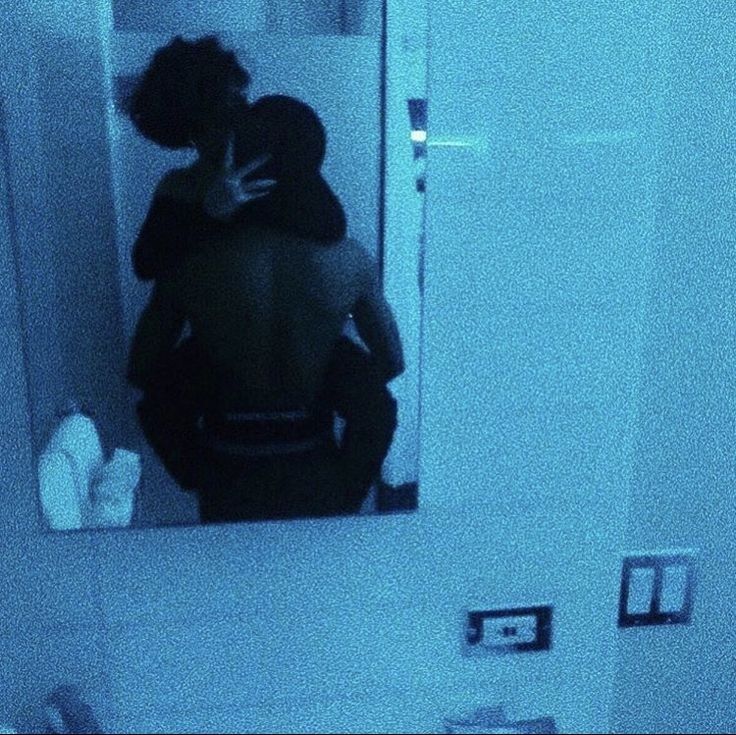 a man and woman in the bathroom looking at themselves in the mirror, with their backs to each other