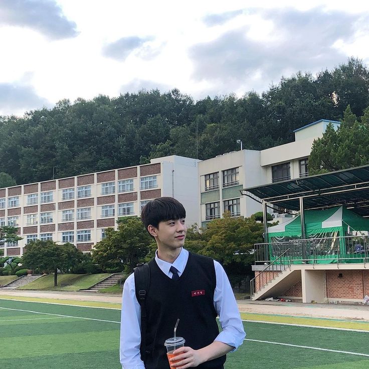 a young man standing on top of a tennis court holding a drink in his hand