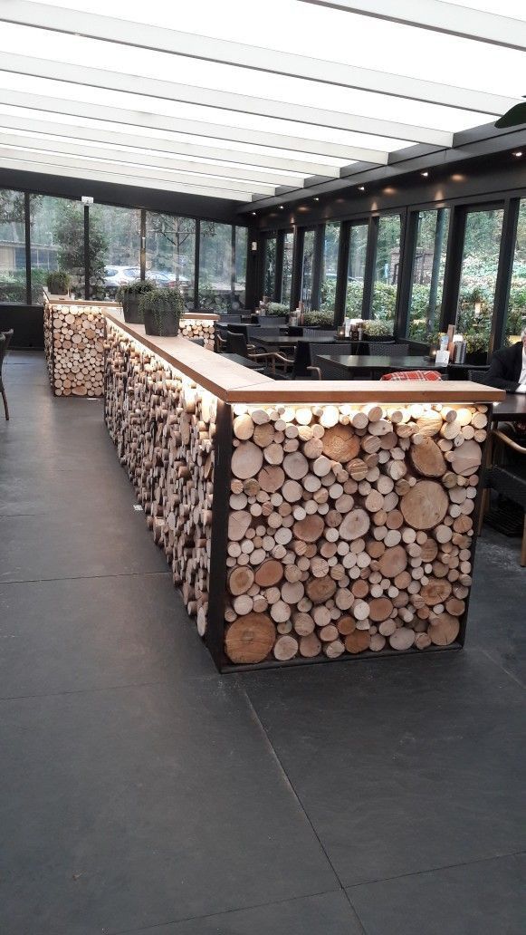 a bar made out of logs in a room with glass walls and floor to ceiling windows