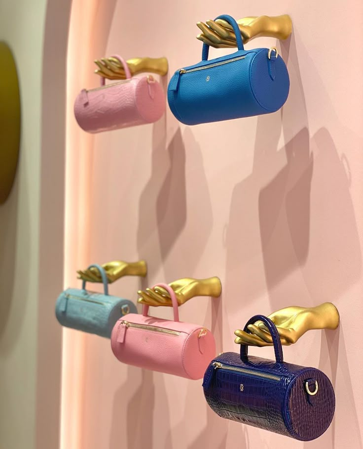 colorful purses are hanging on the wall with gold handles and hooks attached to them