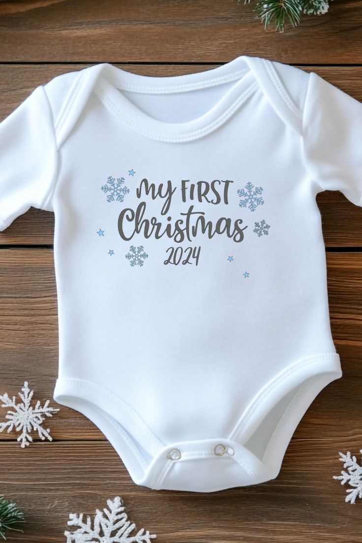 "My First Christmas" baby onesie! Surrounded by delicate snowflakes, this charming outfit is perfect for those holiday photos and will be a cherished keepsake for years to come. Dress your little one in festive spirit and make memories that last a lifetime! Christmas Onsies Baby, My First Christmas Onesie, Christmas Onsies, First Christmas Onesie, Christmas Baby Onesie, Mom Gifts Box, Onesie Ideas, Announcement Onesie, First Christmas Baby