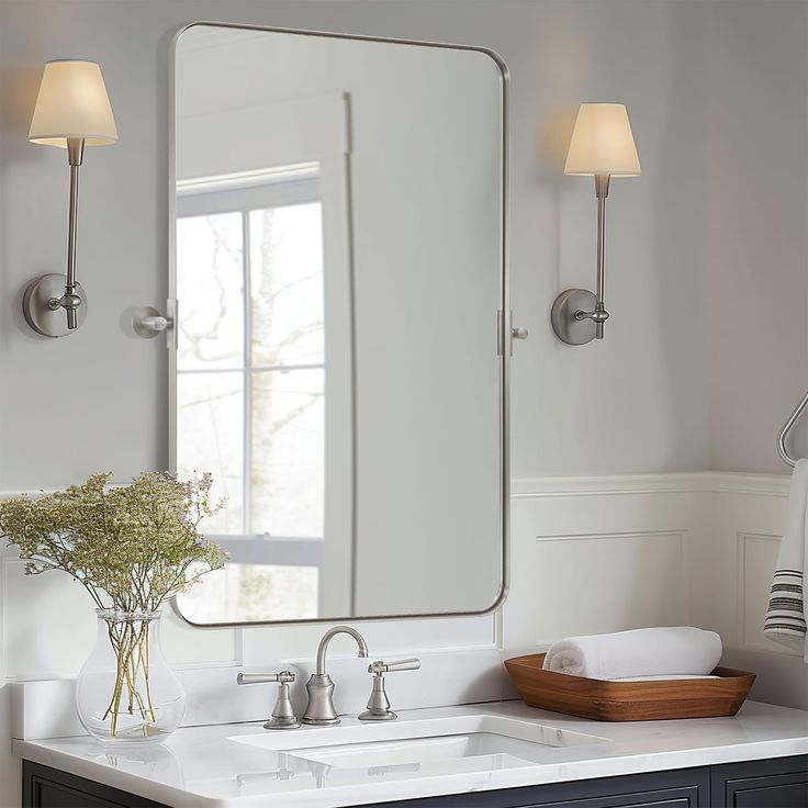 a bathroom sink with a large mirror and two lights on the wall above it,