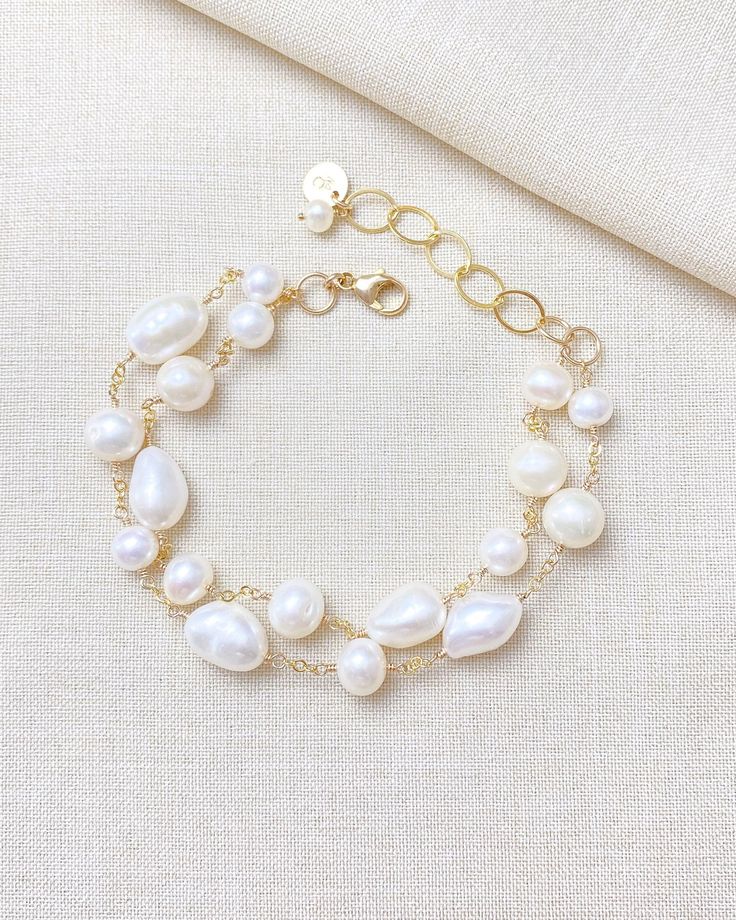 Make a classic and elegant statement with this multi-layered mixed pearl bracelet. Two handcrafted strands of differently shaped and sized pearls create a versatile accessory suitable for weddings, brunches, work, and more. The lobster clasp and extender ensure a secure and adjustable fit. Length: 7.5 inches plus 1.5-inch extender Materials: gold fill, cultured freshwater pearls GIFTING ~ Jewelry gift box included. ~ I am happy to ship directly to the recipient.  Enter their address during check Wedding Baroque Pearl Chain Bracelet, Pearl Beaded Bracelets With Pearl Charm For Wedding, White Pearl Chain Bracelet For Wedding, Wedding Bracelets In Pearl White Baroque Pearl, Baroque Pearl Bracelets For Wedding, Pearl White Baroque Pearl Bracelets For Wedding, Wedding Baroque Pearl Bracelets In Pearl White, Baroque Pearl Wedding Bracelets, Pearl White Bracelet With Pearl Charm For Wedding