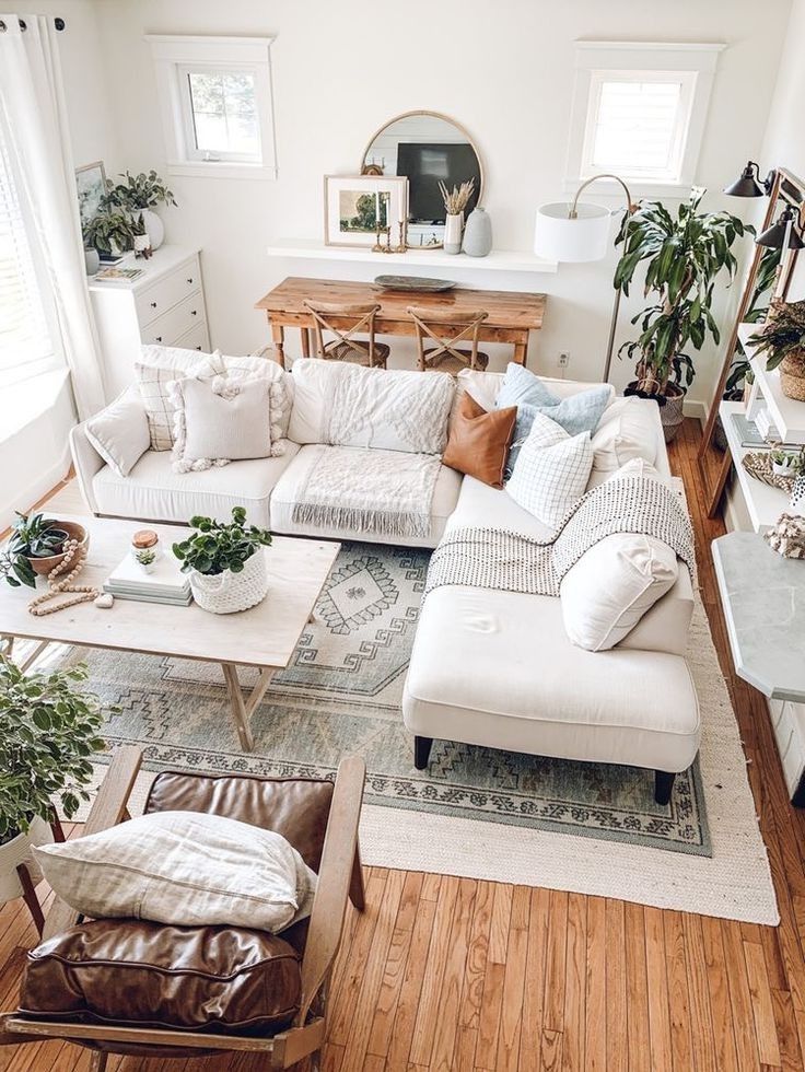 a living room filled with lots of furniture and plants on top of wooden flooring