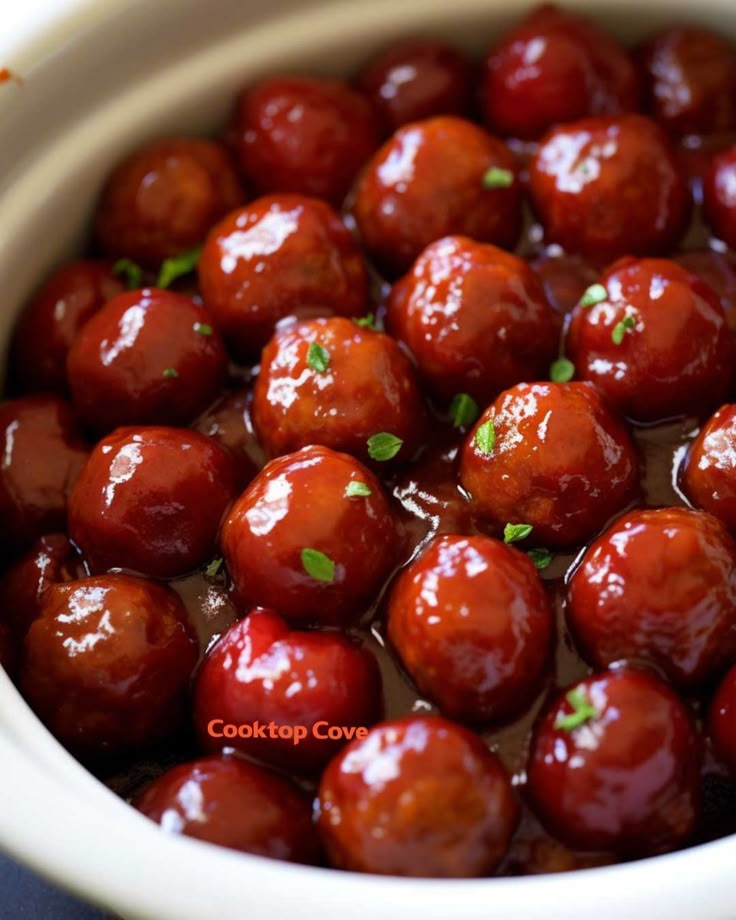 a white bowl filled with cooked meatballs covered in sauce