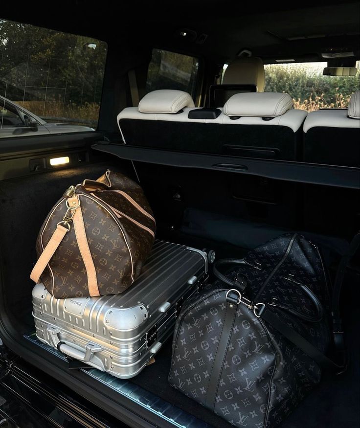 two suitcases are sitting in the back of a car with luggage on it's trunk