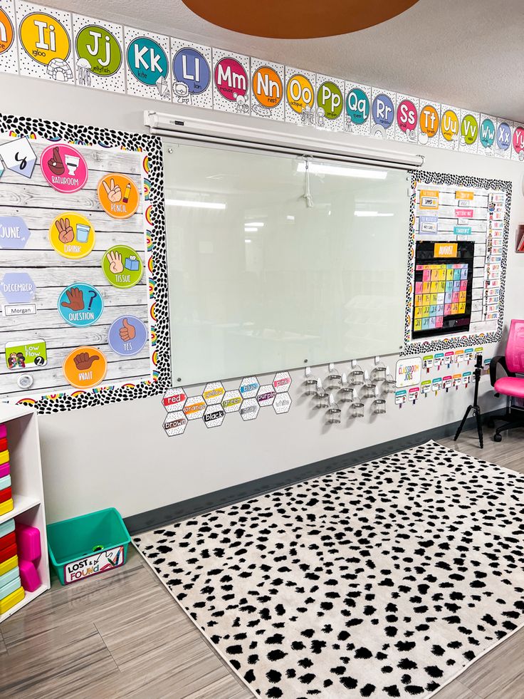 a classroom with whiteboard, black and white polka dot rug and pink chair in the corner