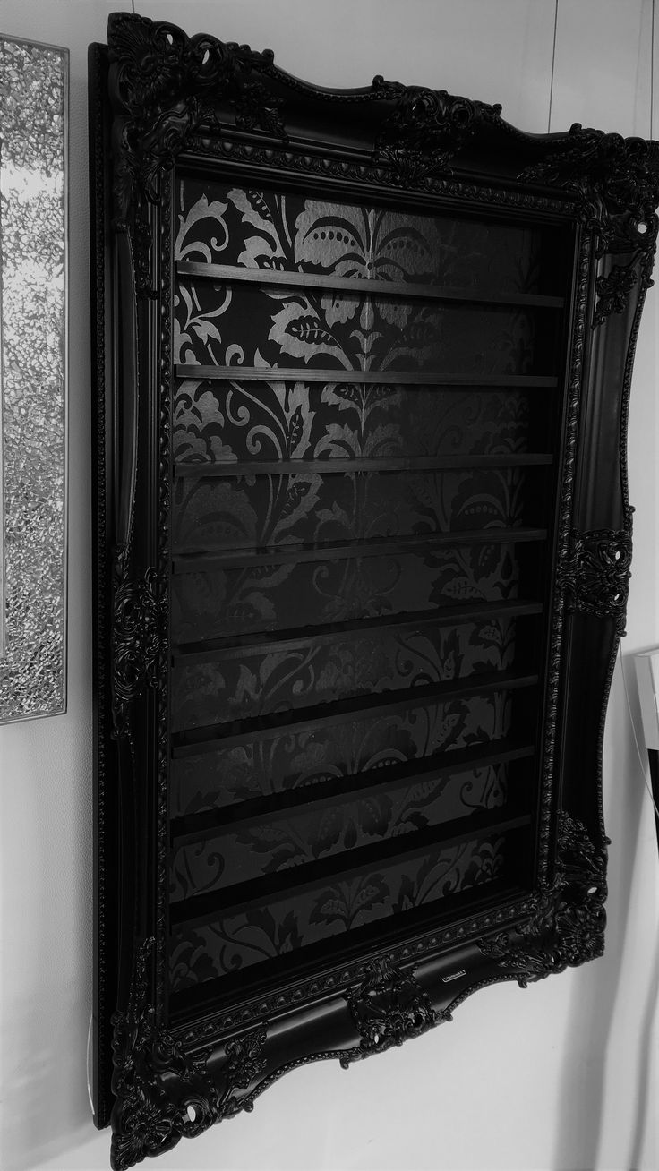 a black and white photo of an ornate frame hanging on the wall next to a mirror