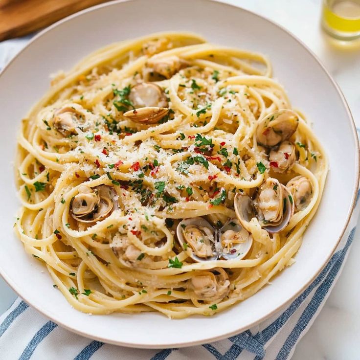 pasta with clams and parmesan cheese in a white bowl on a table