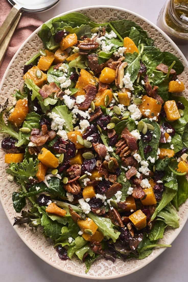 a white plate topped with a salad covered in lots of toppings next to silverware