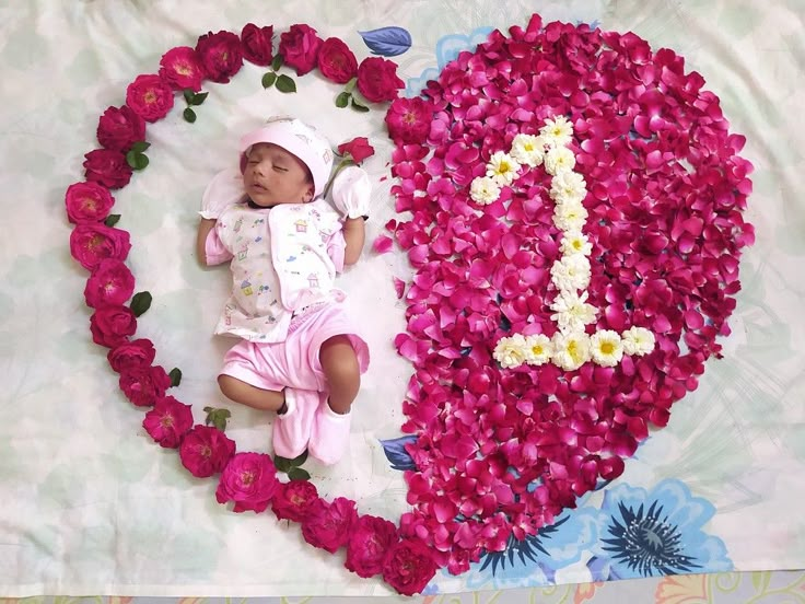 a baby is laying in front of a heart made out of flowers and the number one