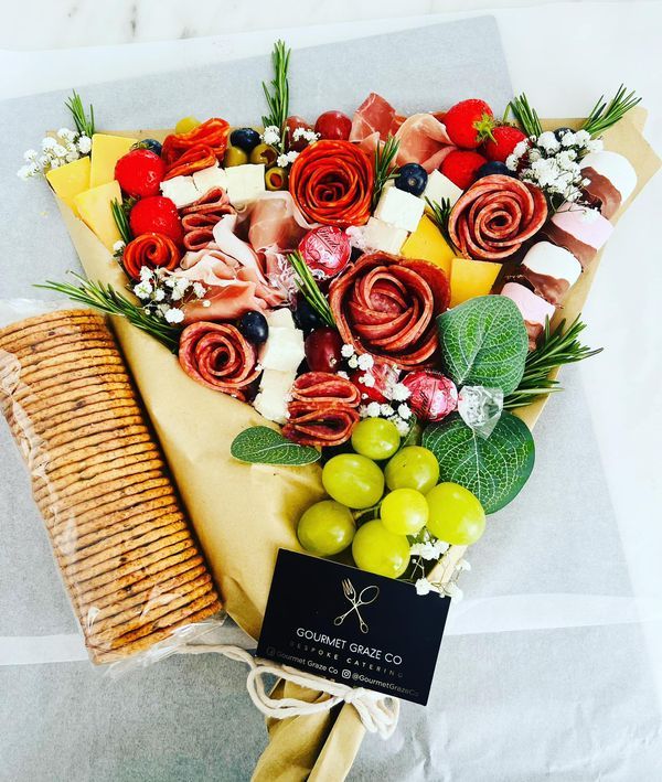 a bouquet of flowers and olives is wrapped in wax paper with a label on it