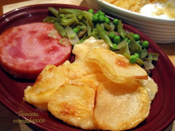 a red plate topped with meat and potatoes next to a bowl of potato chips on a table