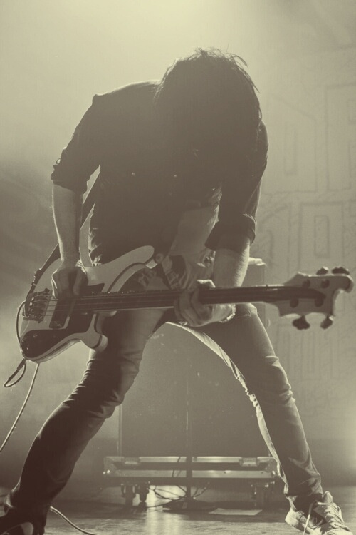 a man holding a guitar while standing on top of a stage