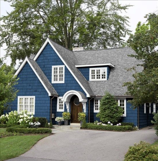 a gray house with white trim and two large windows on the front door is surrounded by greenery