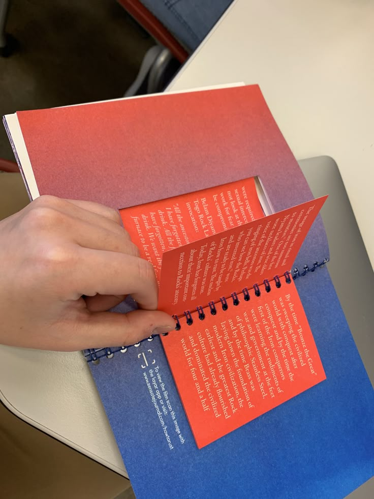 a person holding an open book on top of a table