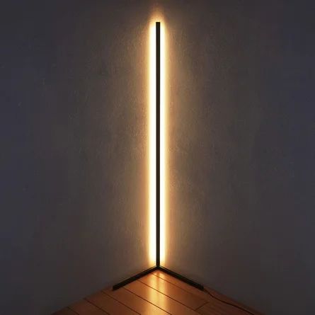 a light that is on top of a wooden floor in front of a white wall