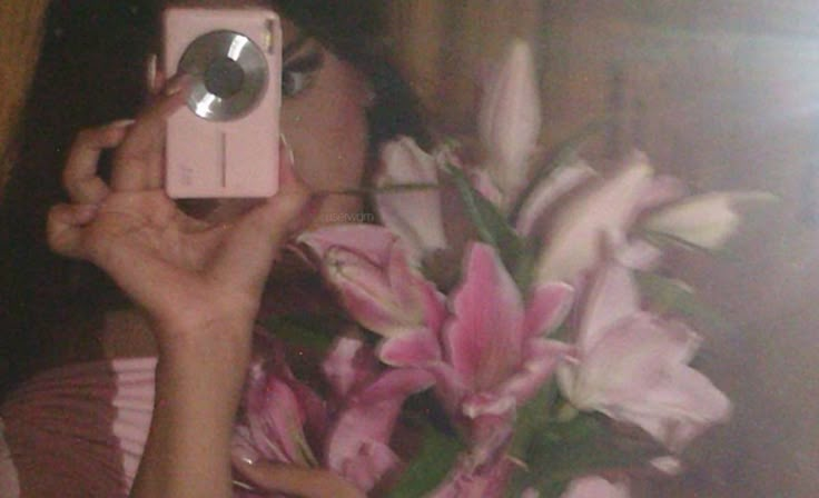 a woman is taking a selfie with her camera and flowers in front of her