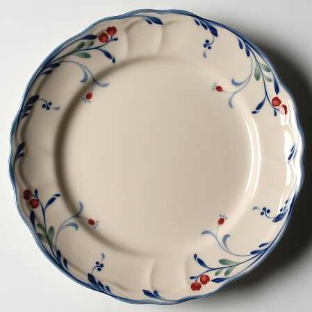 a white plate with blue and red designs on it's rim, sitting on a table