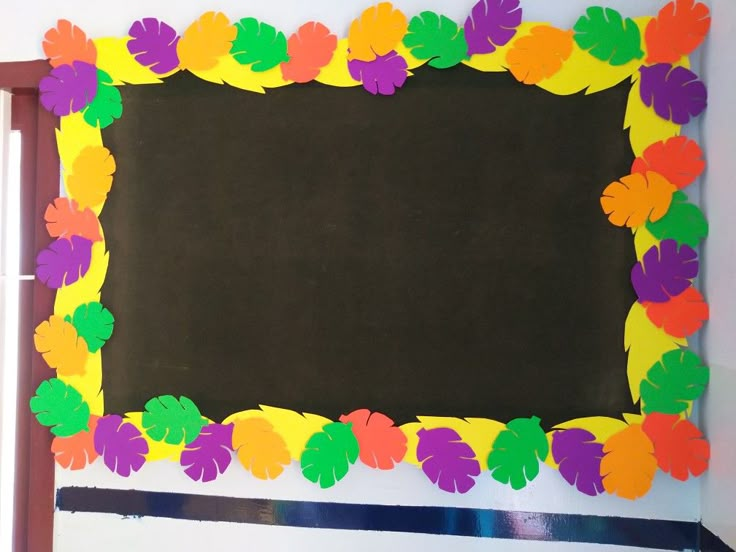 a bulletin board with colorful paper leaves on it and a blackboard in the middle