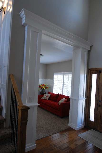 a red couch sitting in the middle of a living room next to a stair case