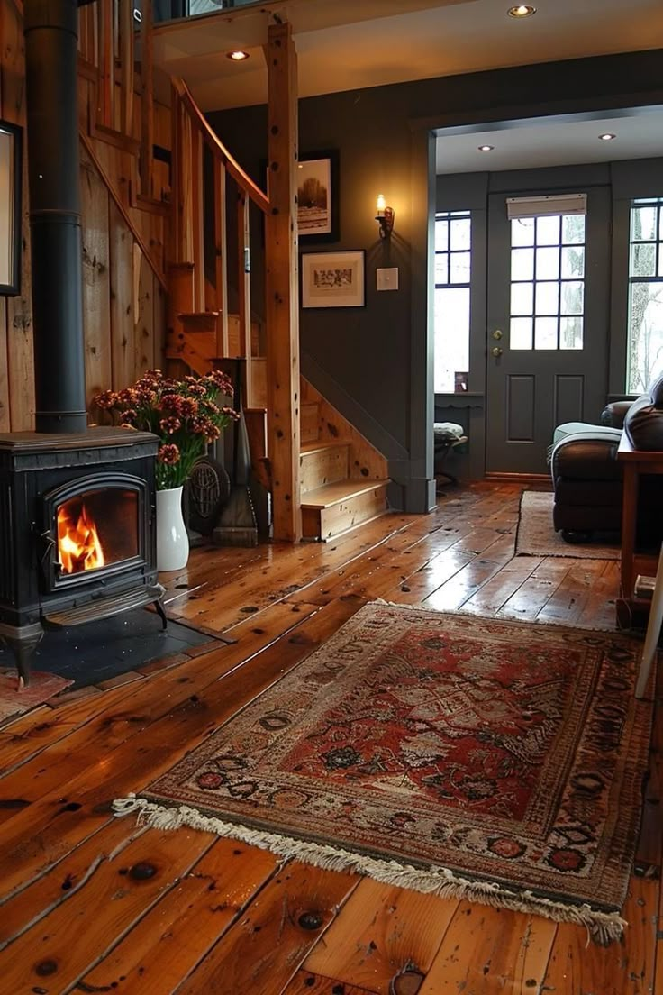 a living room filled with furniture and a fire place next to a wooden floored staircase