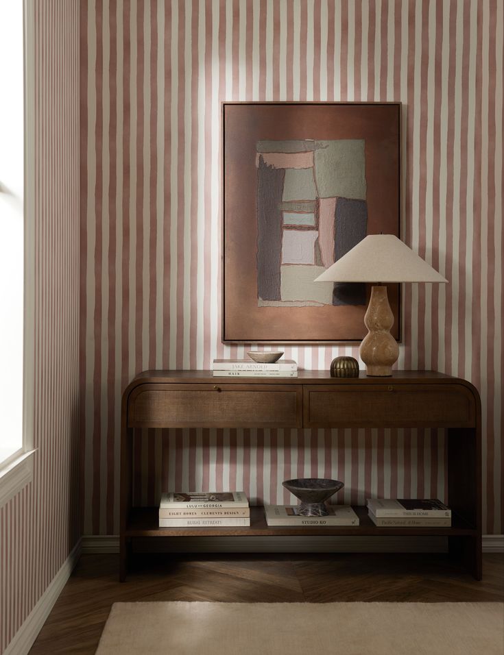 a table with a lamp on it in front of a striped wallpapered room