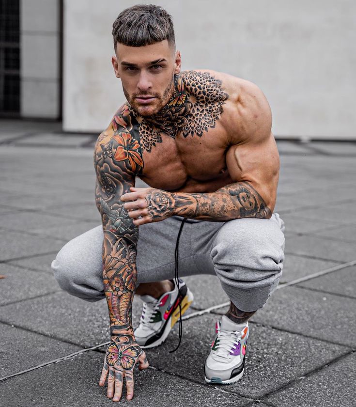 a man with tattoos squatting on the ground