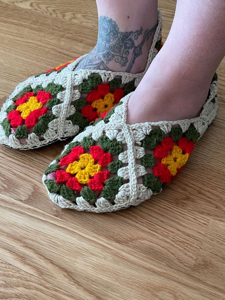 a woman's feet wearing crocheted slippers with flowers on them