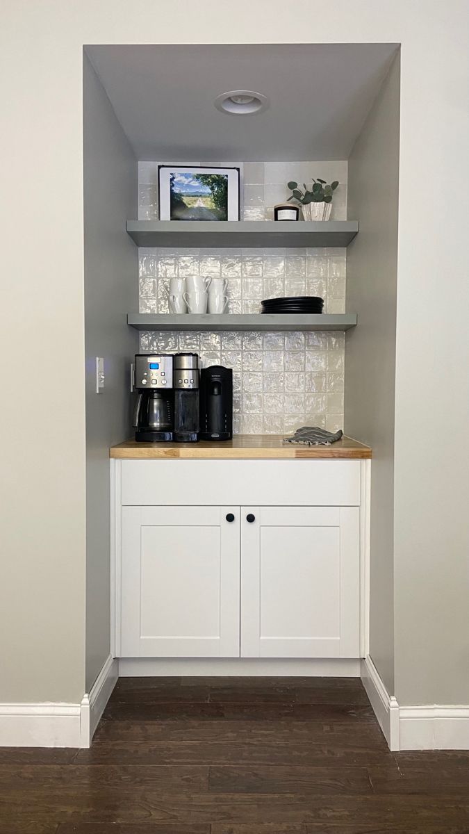 there is a coffee maker on the counter in this small room with white cupboards