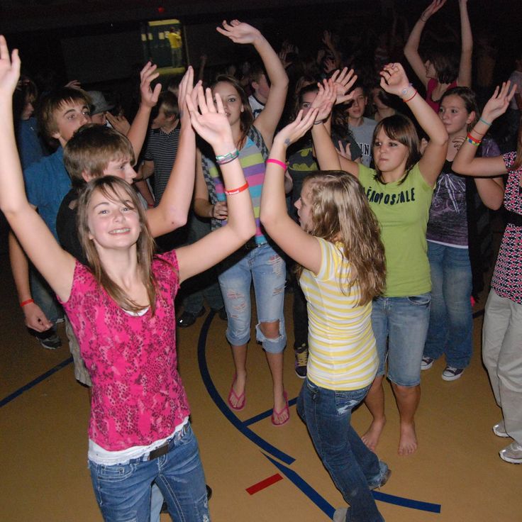 a group of young people standing on top of a dance floor with their hands in the air