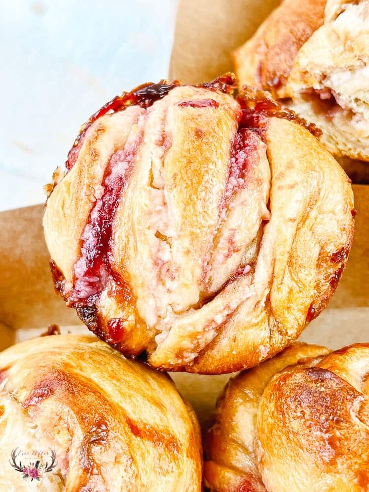 several pastries are stacked on top of each other in a box, with cranberry filling