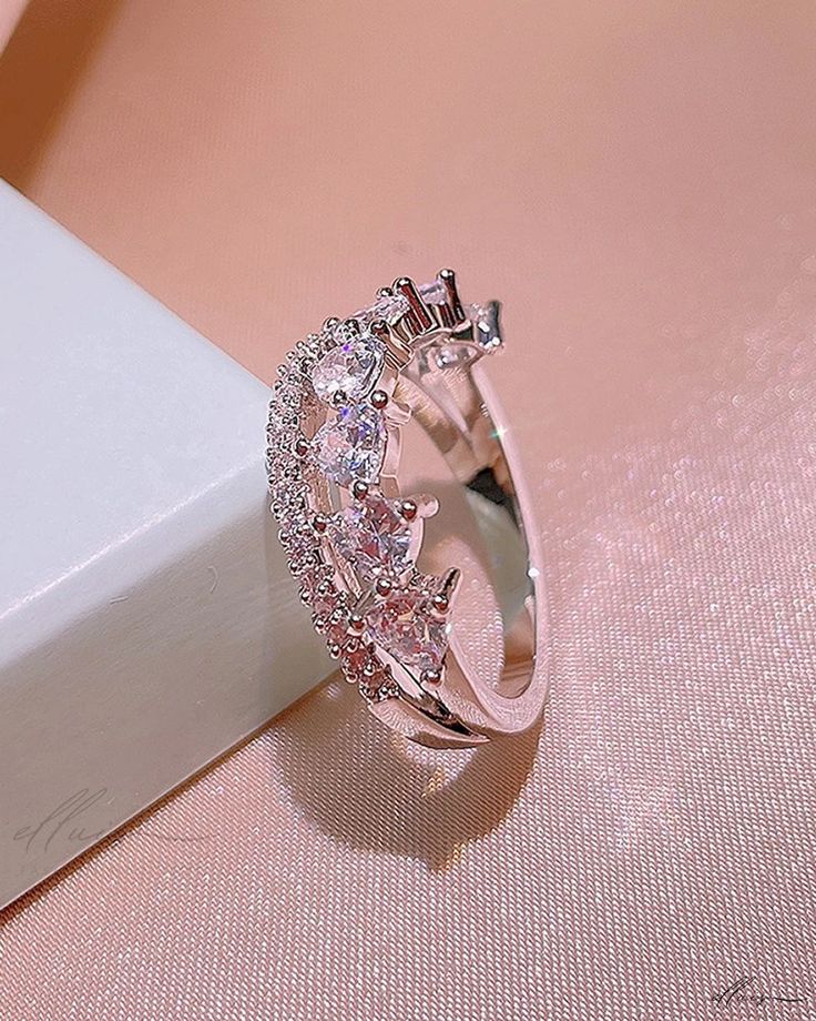 a pink diamond ring sitting on top of a white box